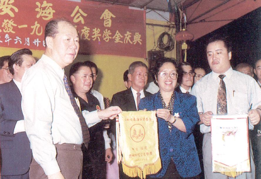 1993 年6 月，泉州市副市长高厚生女士率泉州经商考察团来新期间，应邀出席公会庆典。图为公会荣誉主席黄加种代表公会接受该团赠送的锦旗。